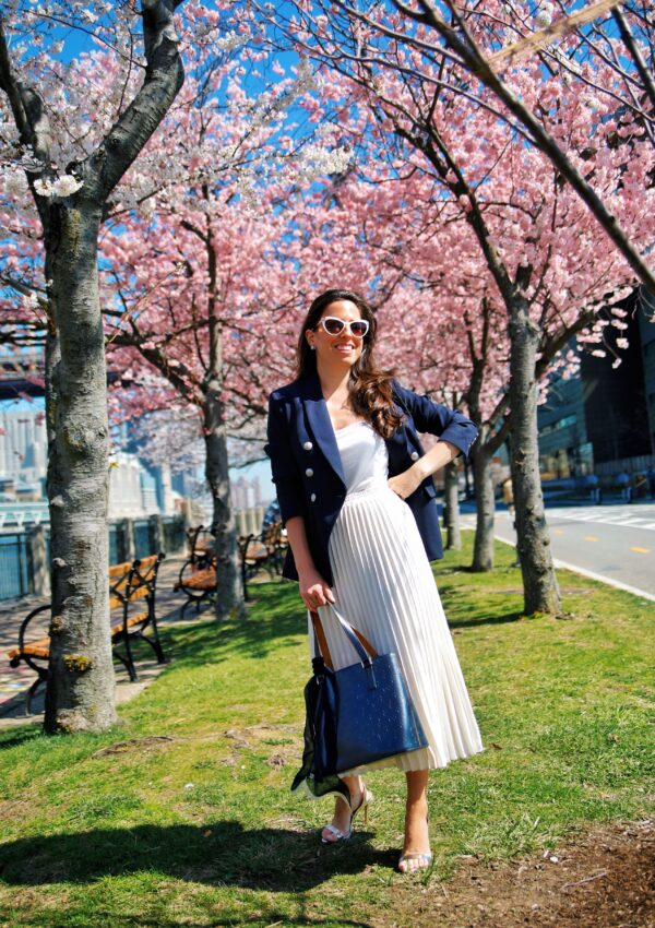 Ana Florentina wearing navy blazer and white pleated skirt spring outfit